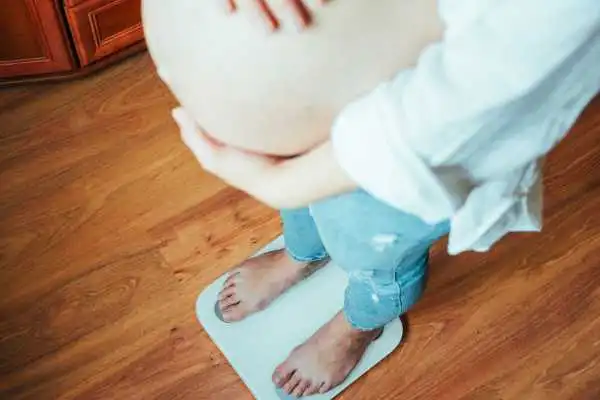 Image of woman weighing herself and experiencing weight gain through pregnancy Tonbridge